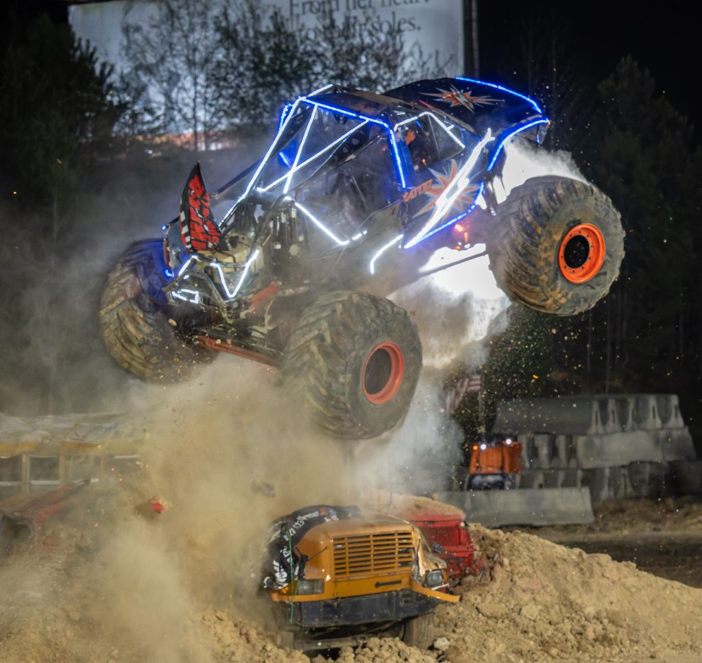 Illuminator Monster Truck hitting a junk school bus crooked with body panels missing and damaged during a freestyle competition