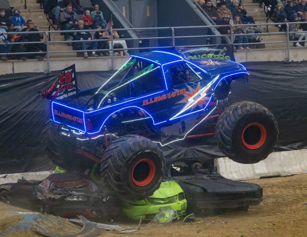 The world's first LED-outlined monster truck Illuminator running over some junk vehicles during a freestyle competition